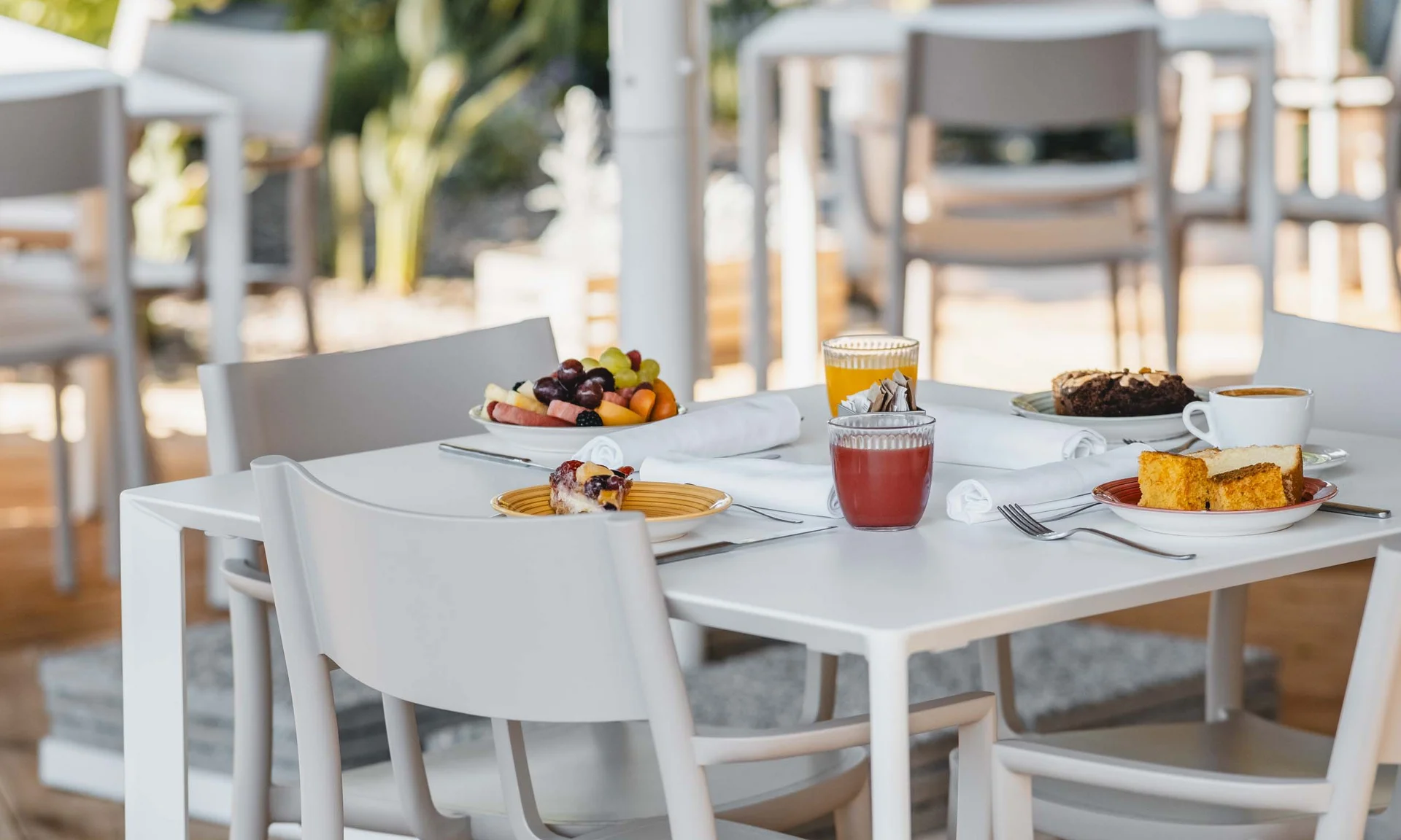 Weißer Tisch mit Frühstück aus Obst, Gebäck, Säften und Kaffee