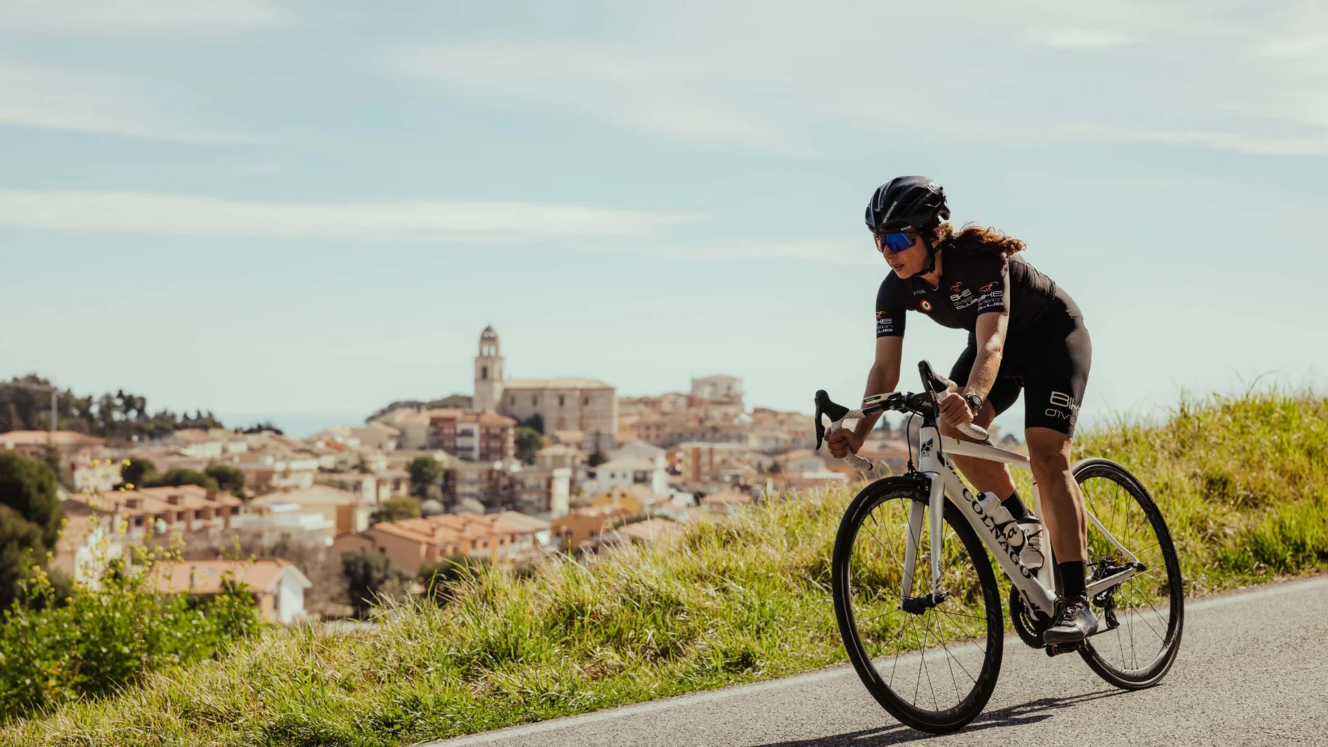 Ciclista donna in abbigliamento da corsa su strada panoramica collinare