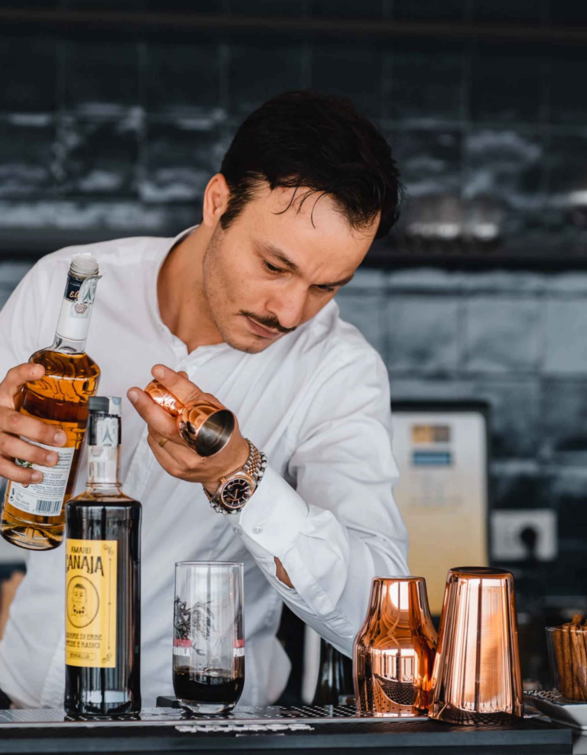 Barkeeper gießt Likör in ein Kupfermessgerät in moderner Bar