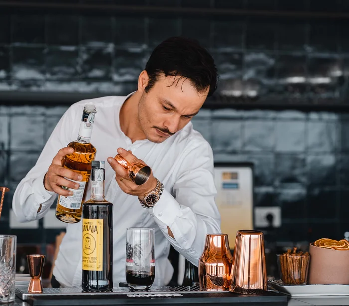 Barista versa liquore in un misurino di rame al bar moderno