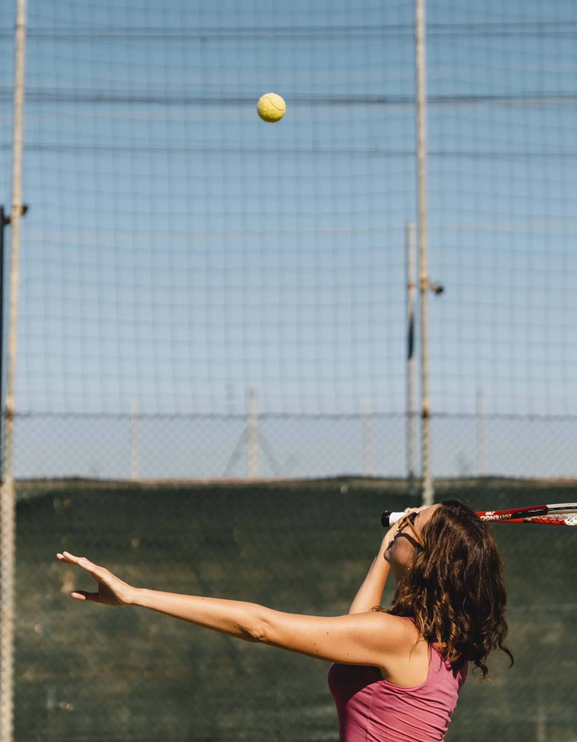 Frau wirft Tennisball bei Spiel im Freien.