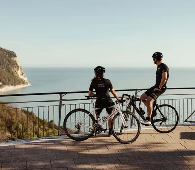 Due ciclisti con bici da corsa guardano il mare da un belvedere panoramico