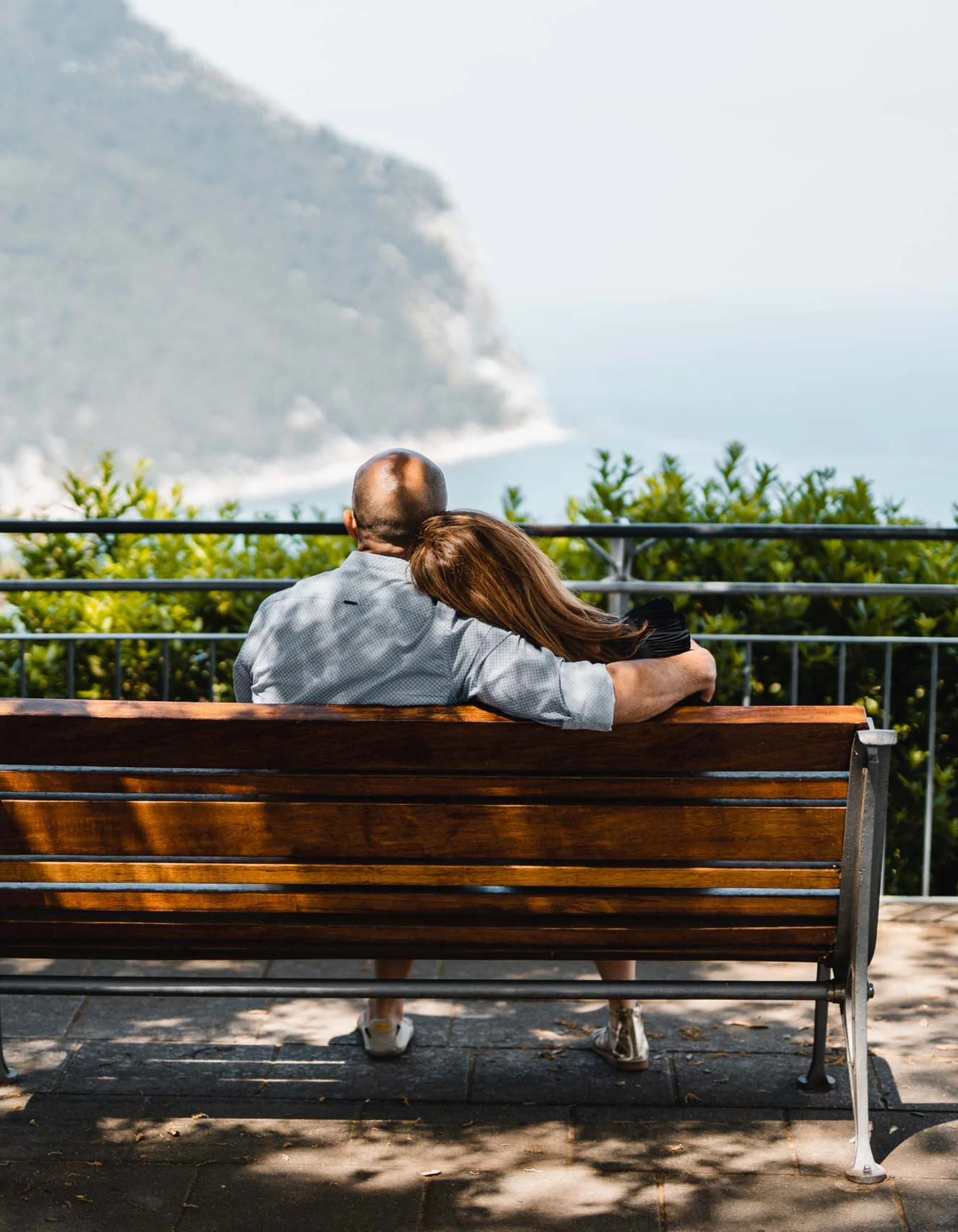 Paar sitzt auf Bank und blickt aufs Meer und die Natur