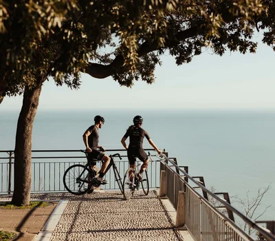 Due ciclisti in abbigliamento sportivo guardano il mare da un belvedere