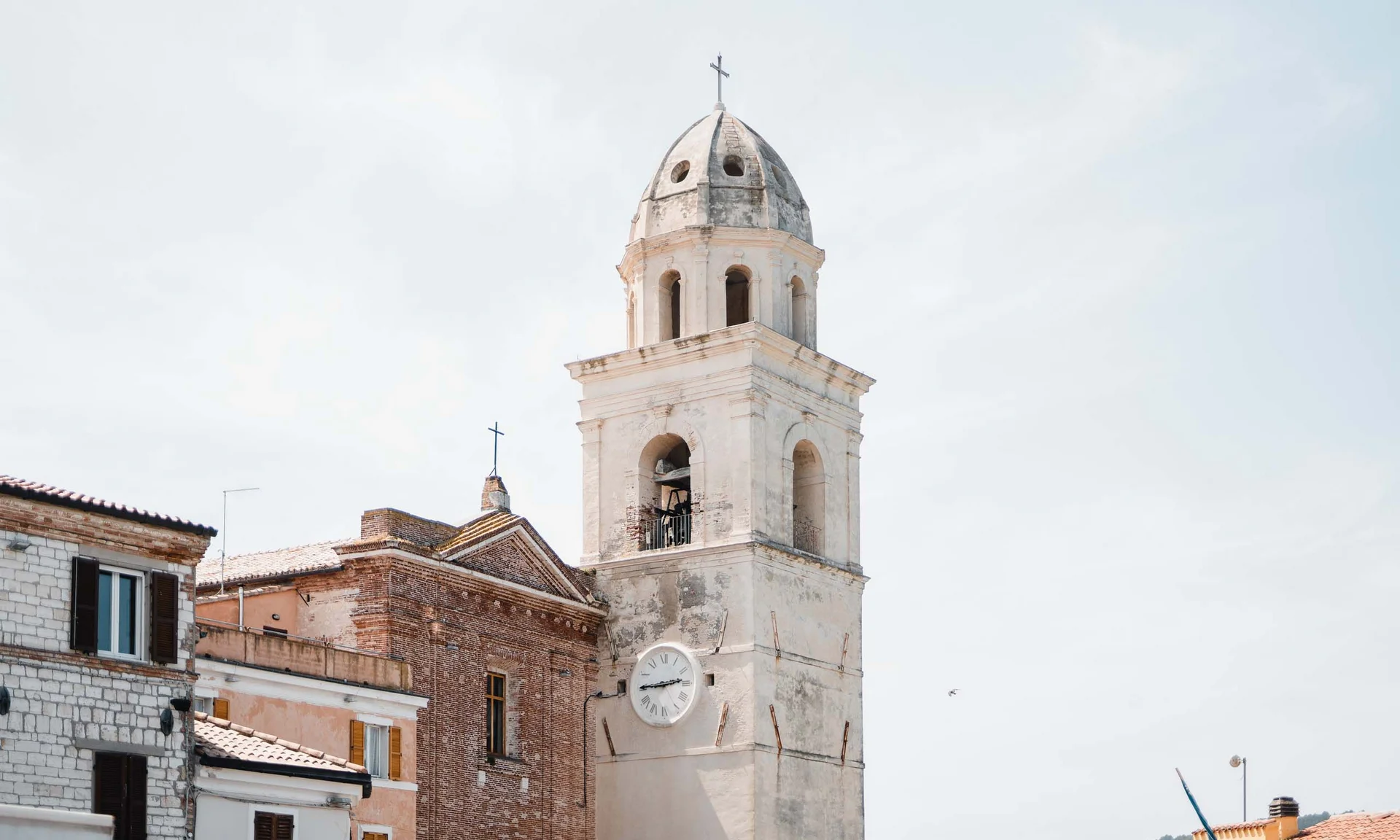 Alter Kirchturm mit Uhr und Kreuz in einem kleinen italienischen Dorf