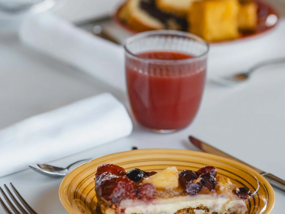 Garden Restaurant: eines der Lokale in unserem Resort Stück Obstkuchen auf gelbem Teller mit Glas rotem Saft