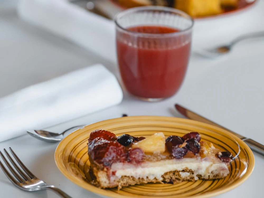 Garden Restaurant: uno dei ristoranti del nostro resort Fetta di torta alla frutta su piatto giallo con bicchiere di succo rosso