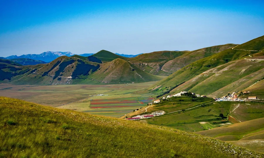 Grüne Berglandschaft mit Dorf und blauem Himmel
