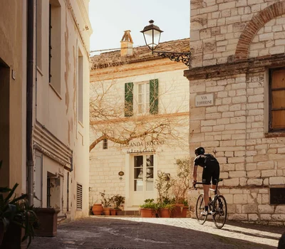 Ciclista che pedala in una strada di ciottoli in un villaggio storico