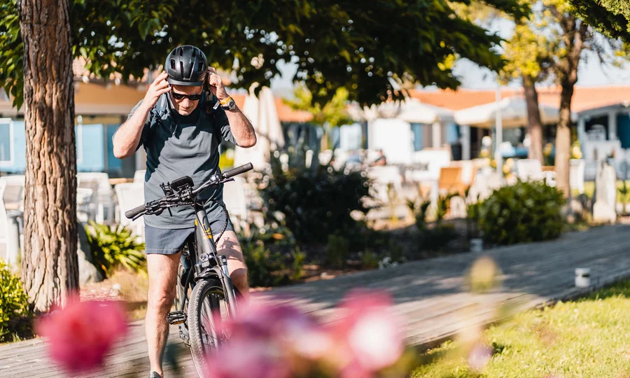 Mann setzt sich Helm auf, bereit zum Radfahren im sonnigen Park