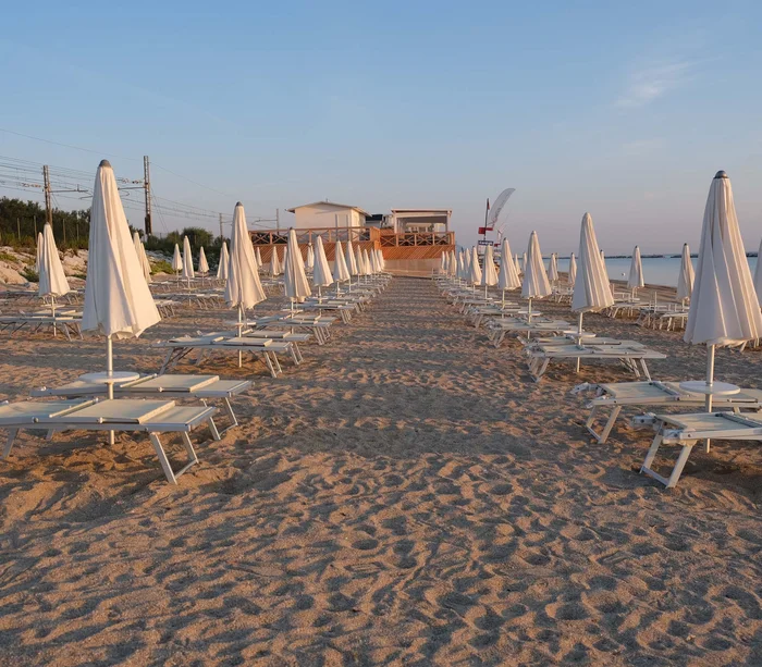 Ombrelloni e lettini chiusi su una spiaggia deserta al tramonto