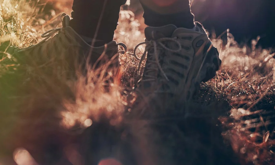 Wanderschuhe im Gras mit Sonnenlicht und Lichtreflexen