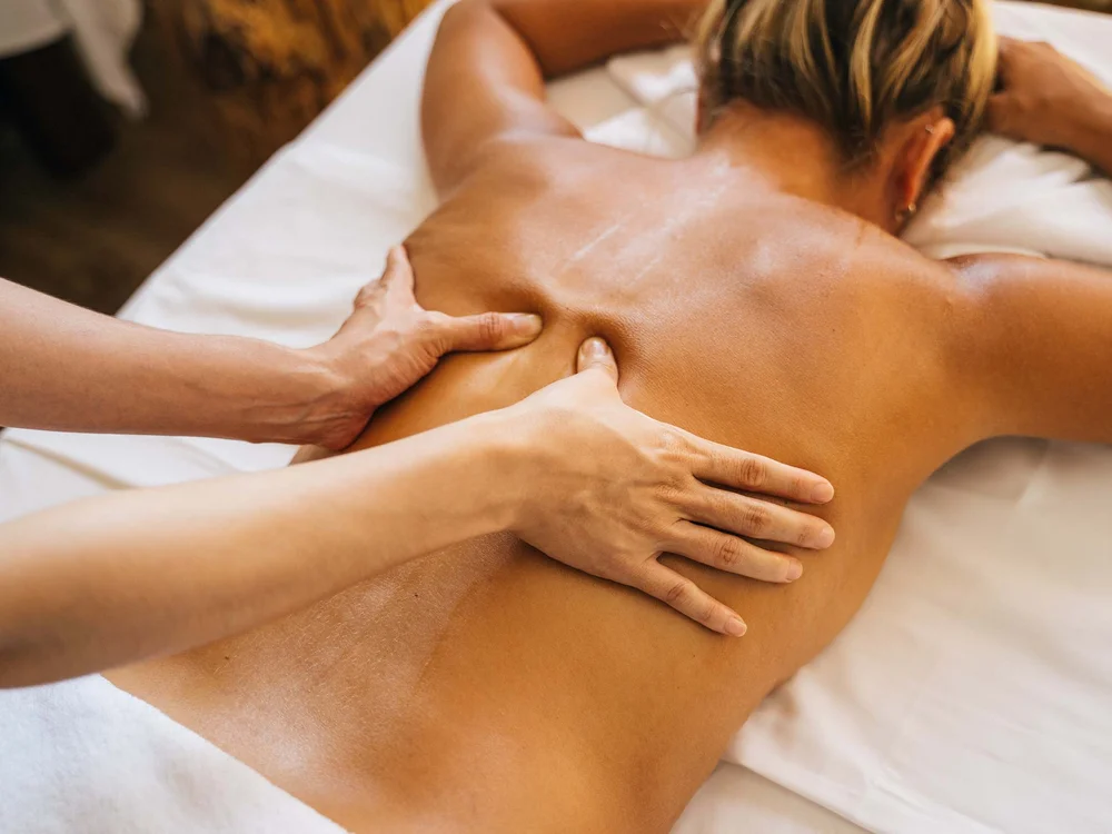 Rückenmassage bei einer Frau, die auf einer Liege liegt