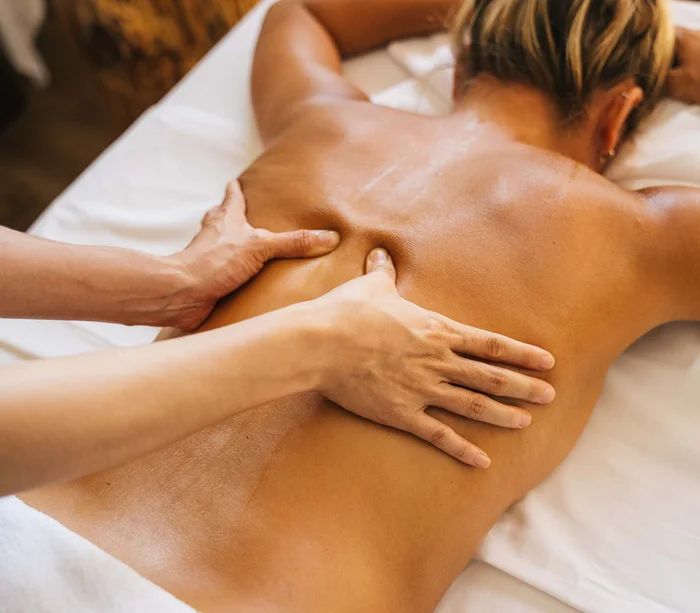 Rückenmassage bei einer Frau, die auf einer Liege liegt