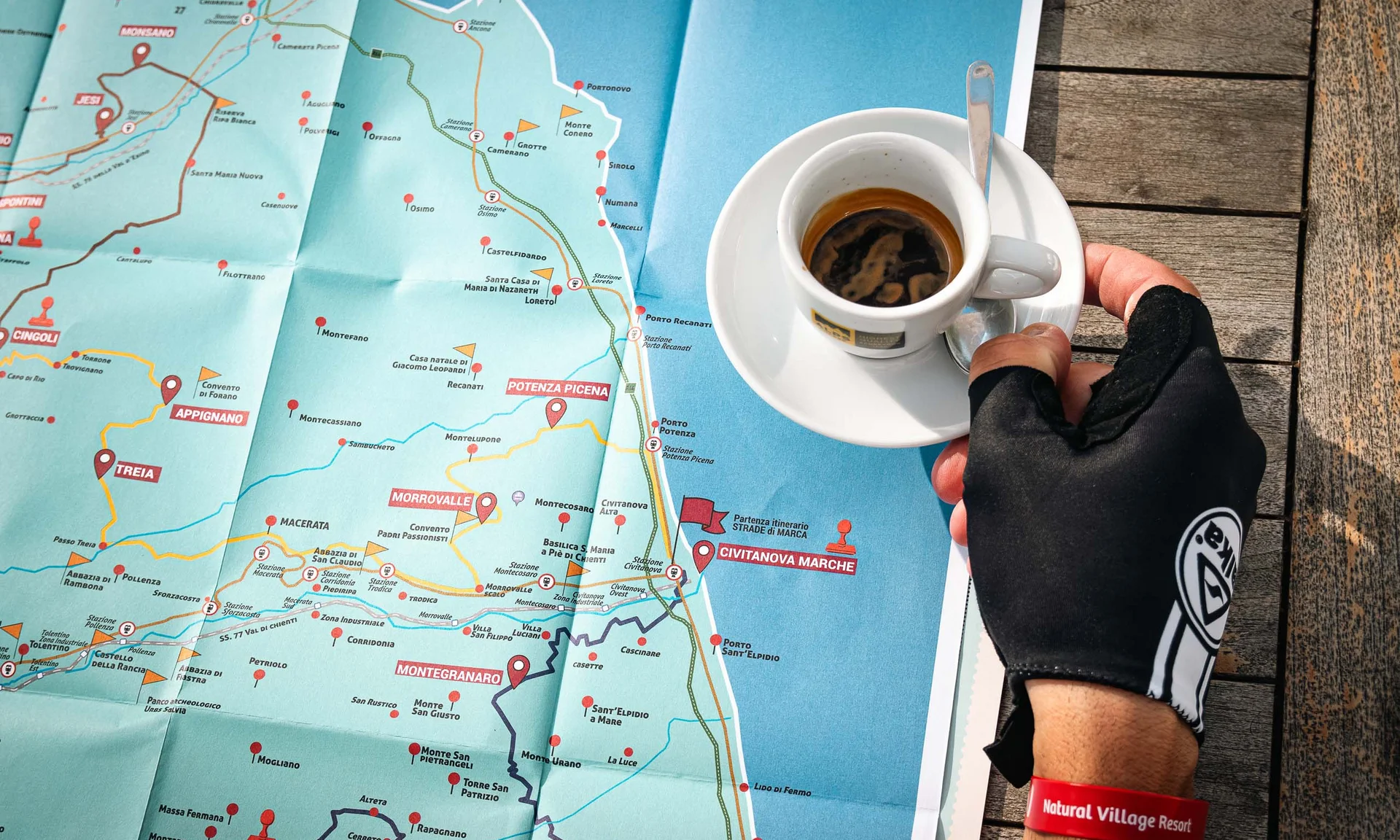 Hand mit Handschuh und Kaffee über detaillierter Karte italienischer Städte