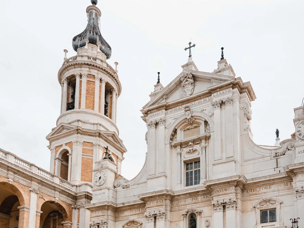 Paar geht vor einer historischen Kirche mit Turm und Statue