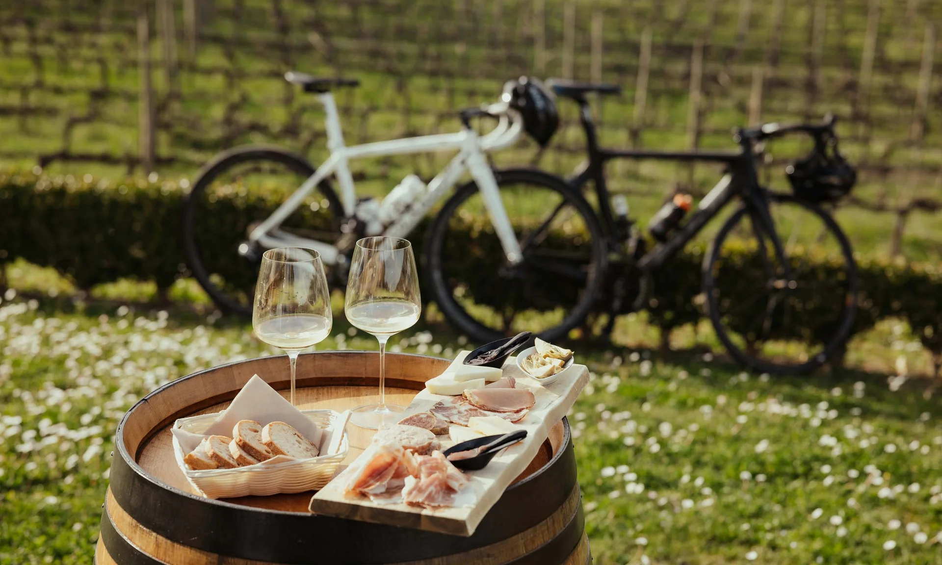 Weißwein, Wurstbrett und Brot auf Fass im Freien mit zwei Fahrrädern