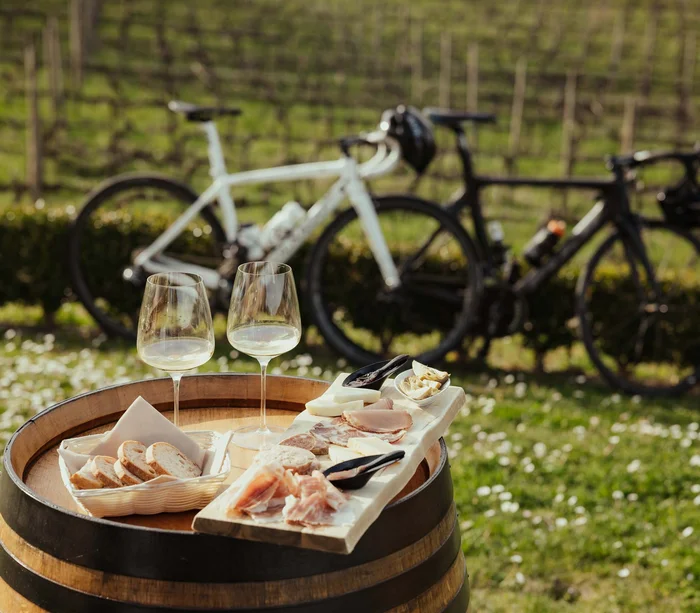 Weißwein, Wurstbrett und Brot auf Fass im Freien mit zwei Fahrrädern