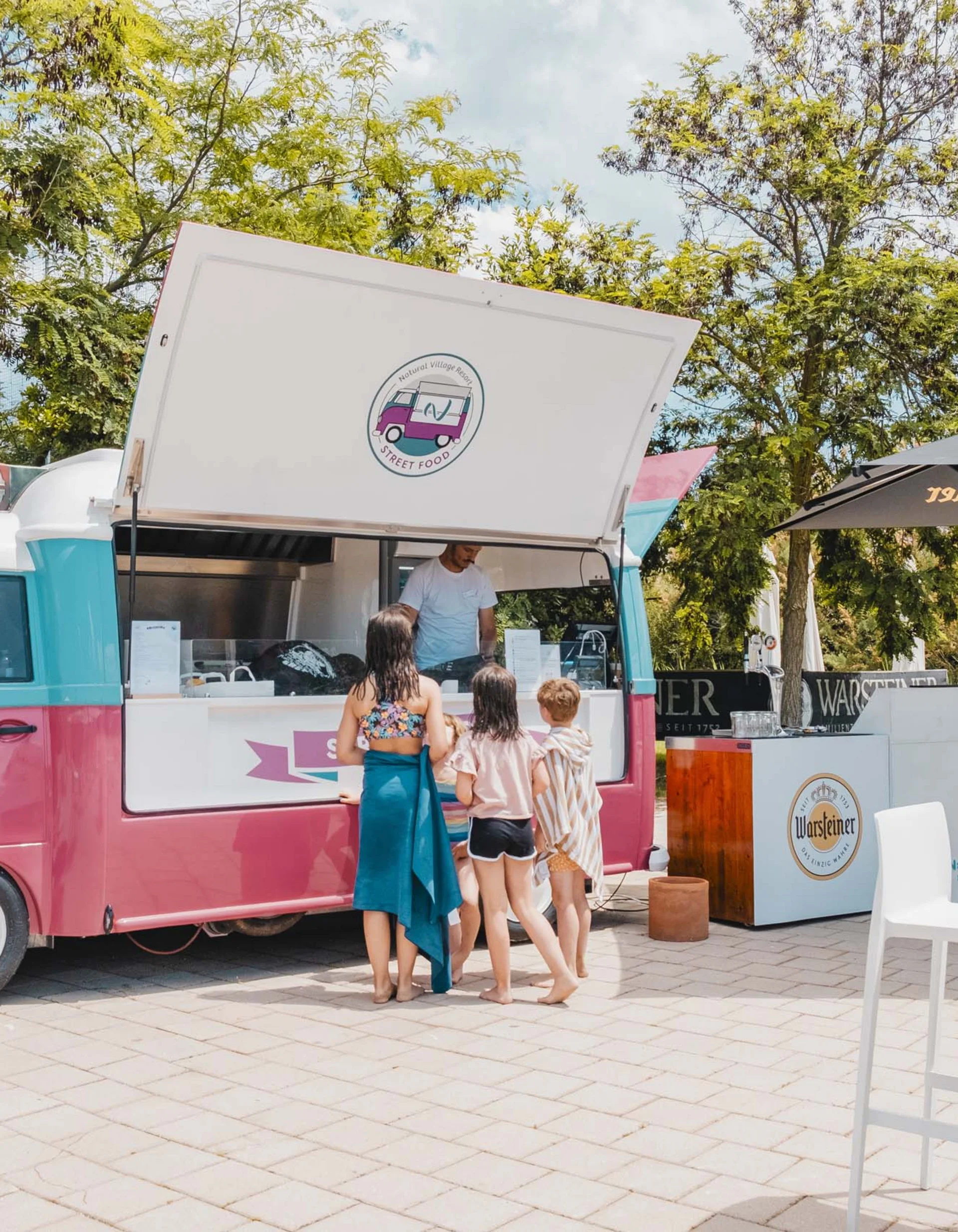 Kinder stehen Schlange vor einem bunten Street-Food-Wagen im Freien
