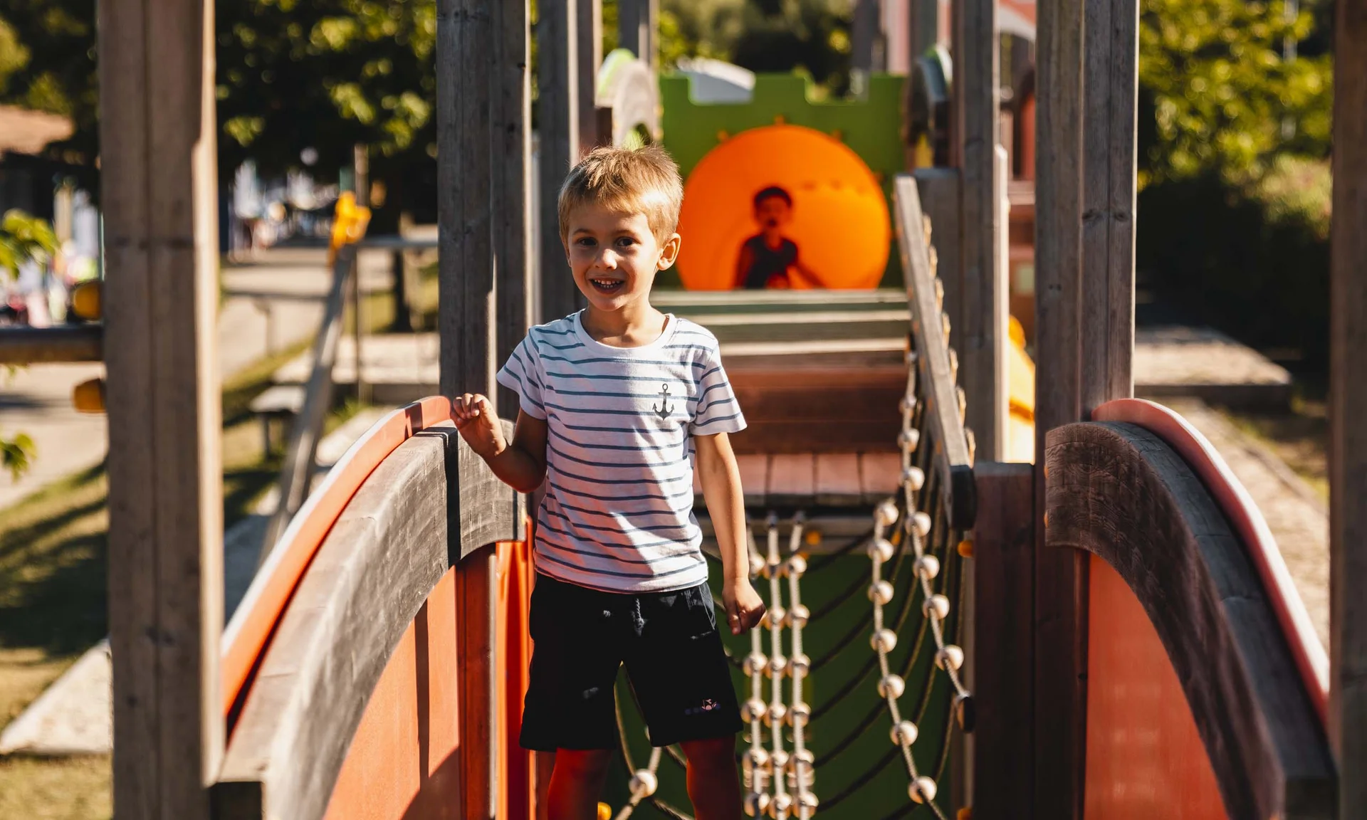 Kind spielt auf einer Holzspielstruktur auf dem Spielplatz im Freien