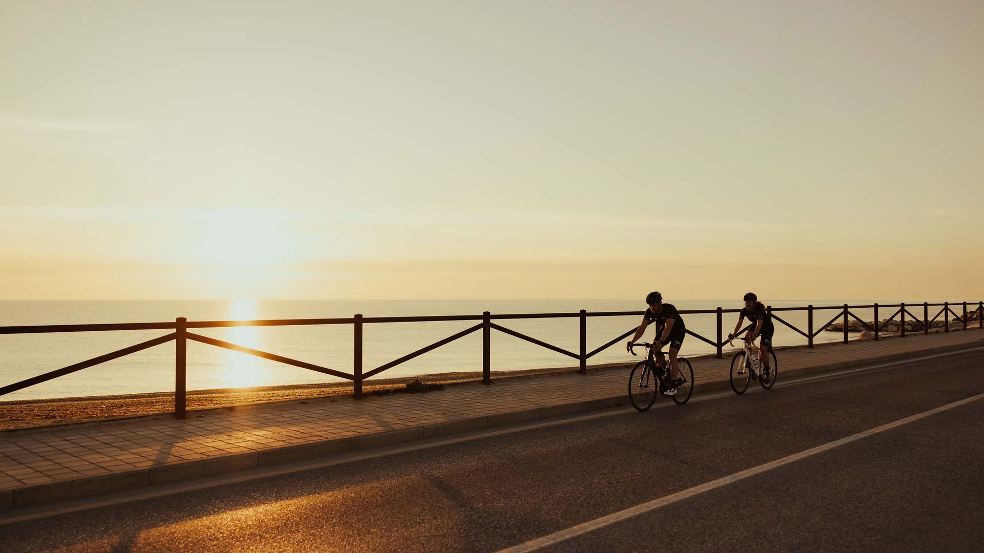 Zwei Radfahrer bei Sonnenuntergang auf einer Küstenstraße