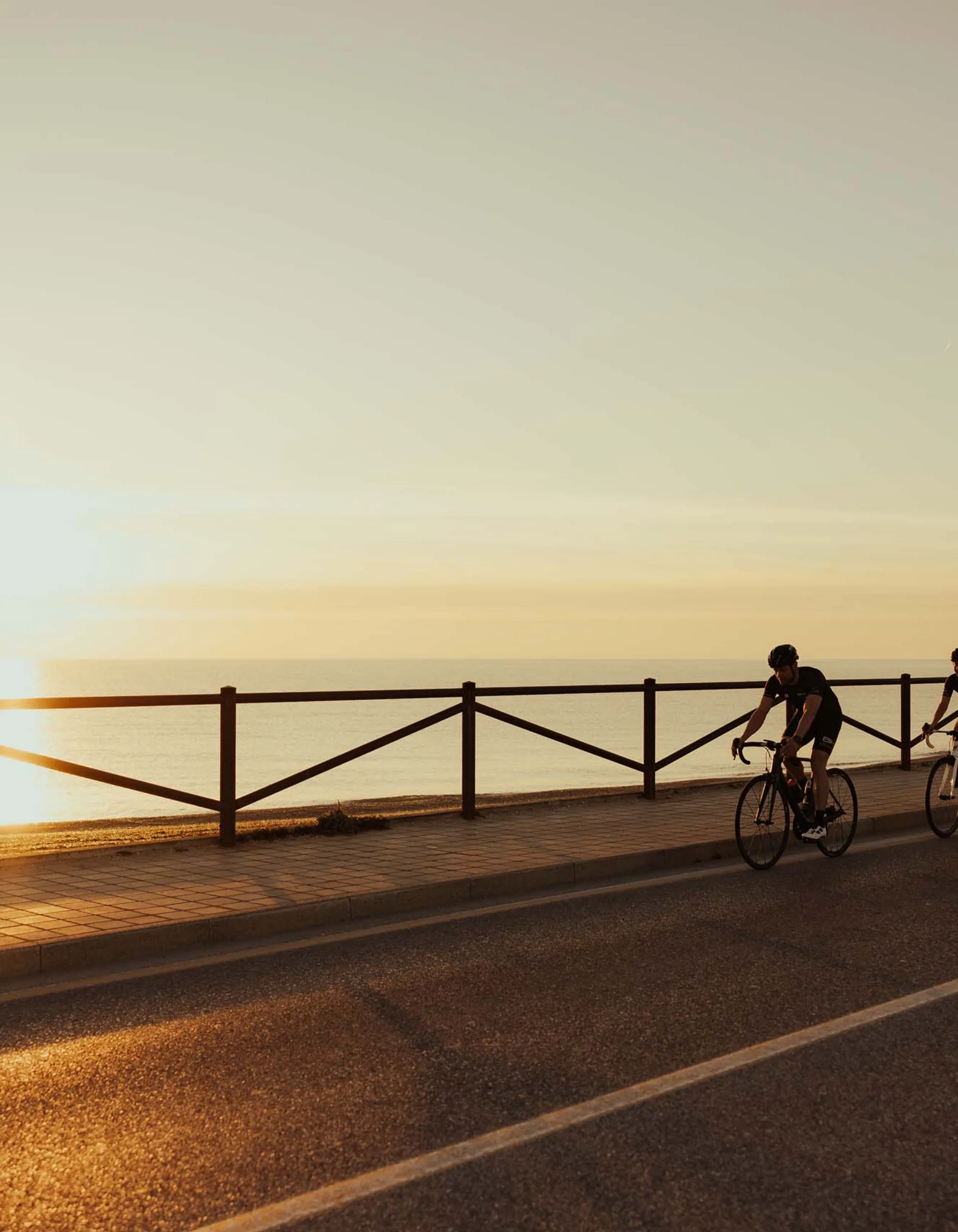 Zwei Radfahrer bei Sonnenuntergang auf einer Küstenstraße