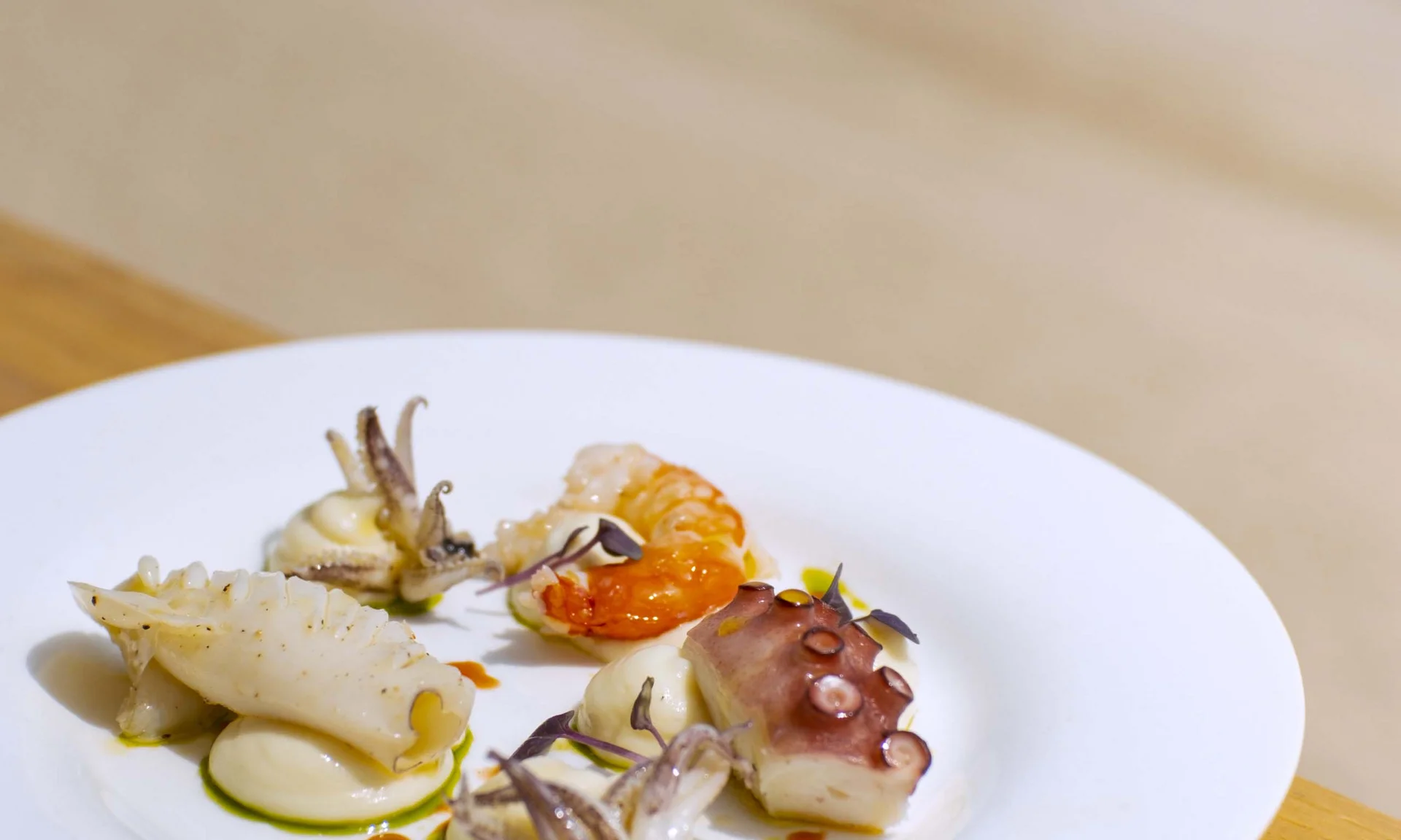Teller mit Meeresfrüchten: Oktopus, Garnele und Tintenfisch auf weißer Creme