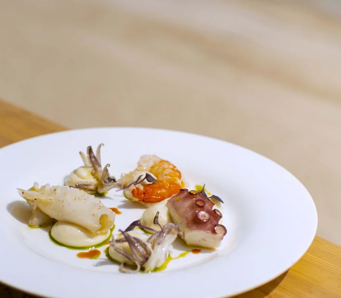 Teller mit Meeresfrüchten: Oktopus, Garnele und Tintenfisch auf weißer Creme