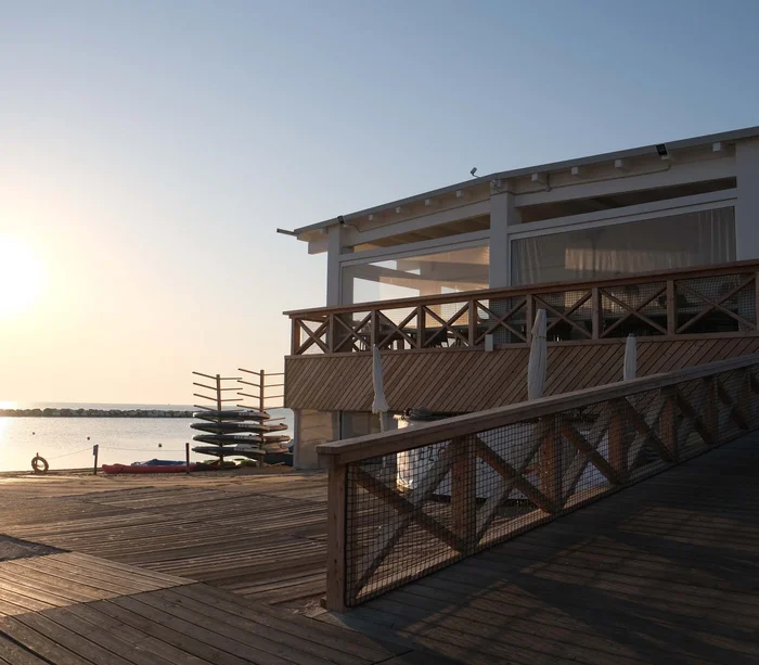 Tramonto sul mare con struttura in legno e kayak impilati sulla spiaggia
