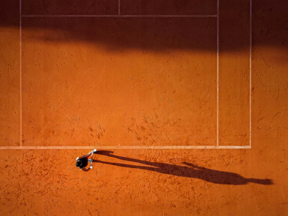 Sport & more at Natural Village Resort Tennis player on clay court aerial view with long shadow