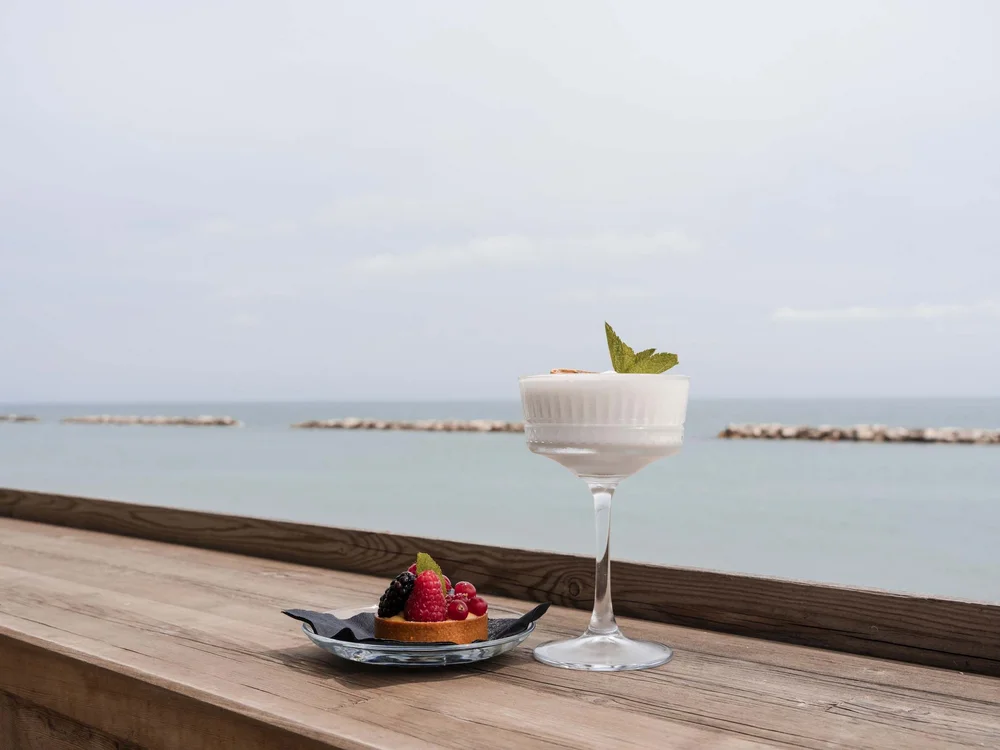 Dessert mit Creme und Beeren auf einem Holztisch am Meer