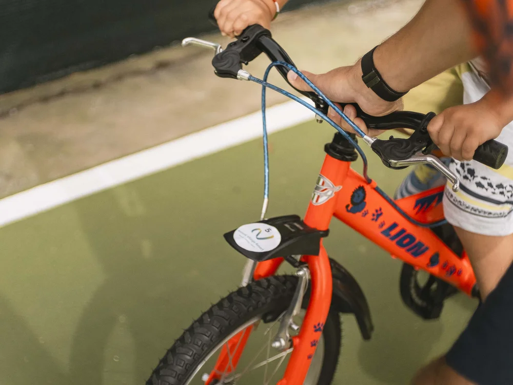 Bambino impara a andare in bici con l'aiuto di un adulto