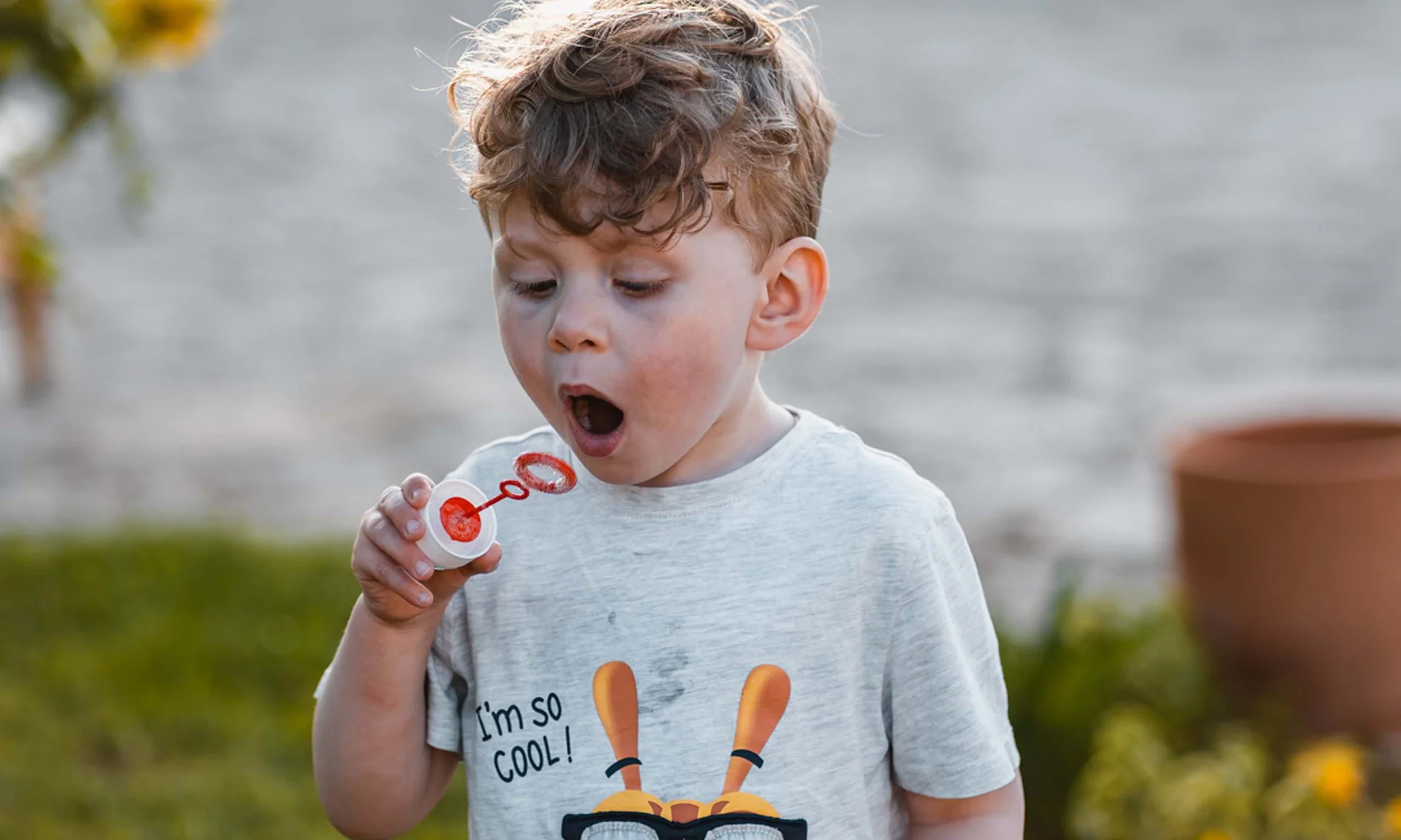 Kind bläst Seifenblasen im Garten mit T-Shirt mit Giraffenmotiv