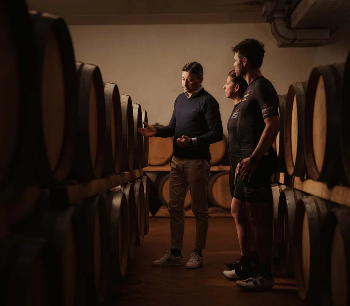 Personen in einem Weinkeller zwischen Holzfässern zur Weinlagerung