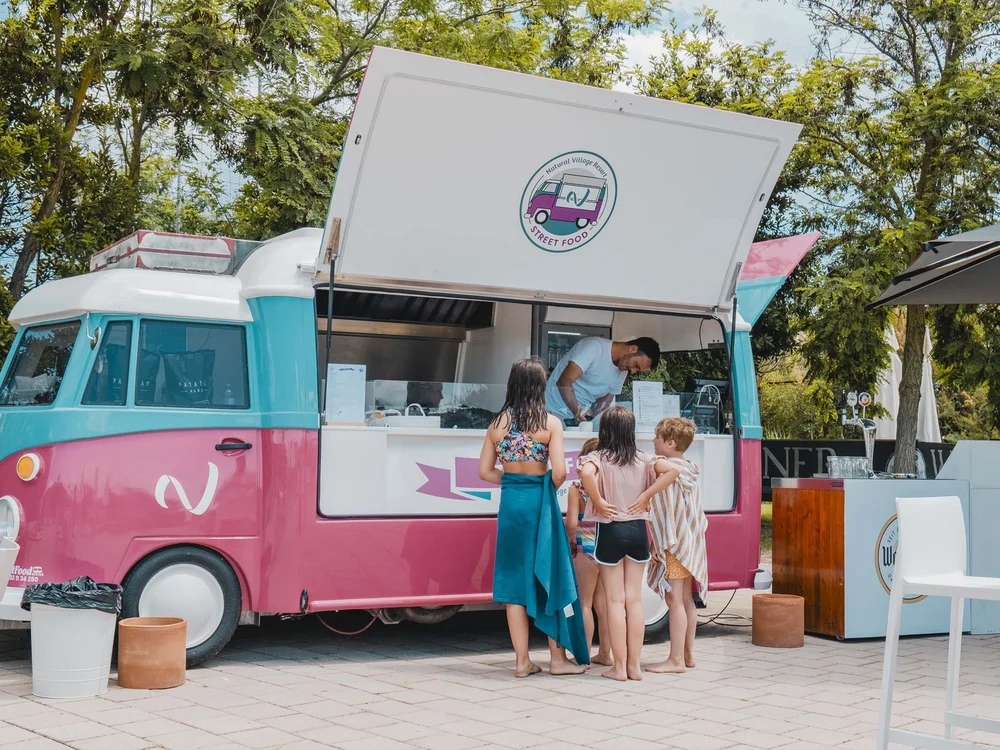Bimbi in costume ordinano al food truck rosa e azzurro all'aperto vicino a tavoli