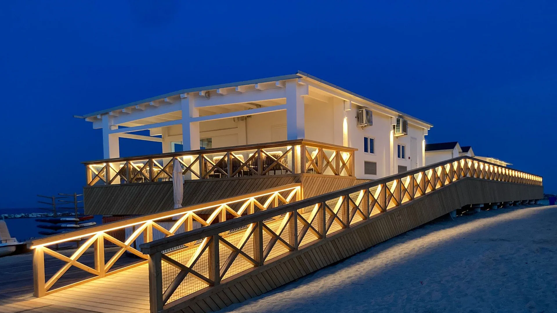 Beleuchtete Rampe zu weißem Gebäude am Strand bei Nacht