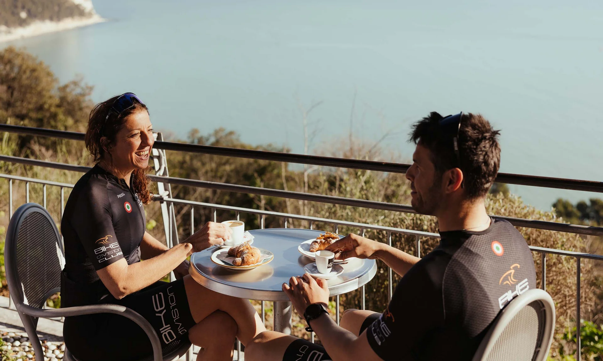 Zwei Radfahrer trinken Kaffee und essen Croissants mit Meerblick