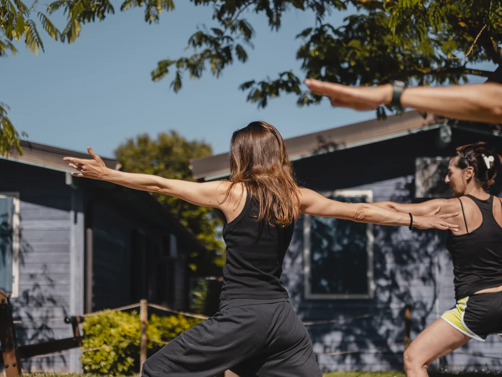 Due donne che fanno yoga all'aperto in un giardino soleggiato