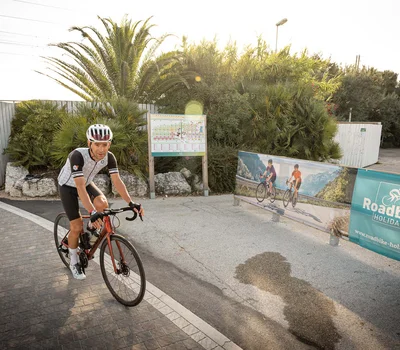 Ciclista su strada vicino a cartello pubblicitario Roadbike Holidays
