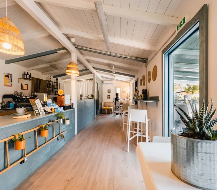 Interno luminoso di un bar con bancone, tavoli e decorazioni moderne
