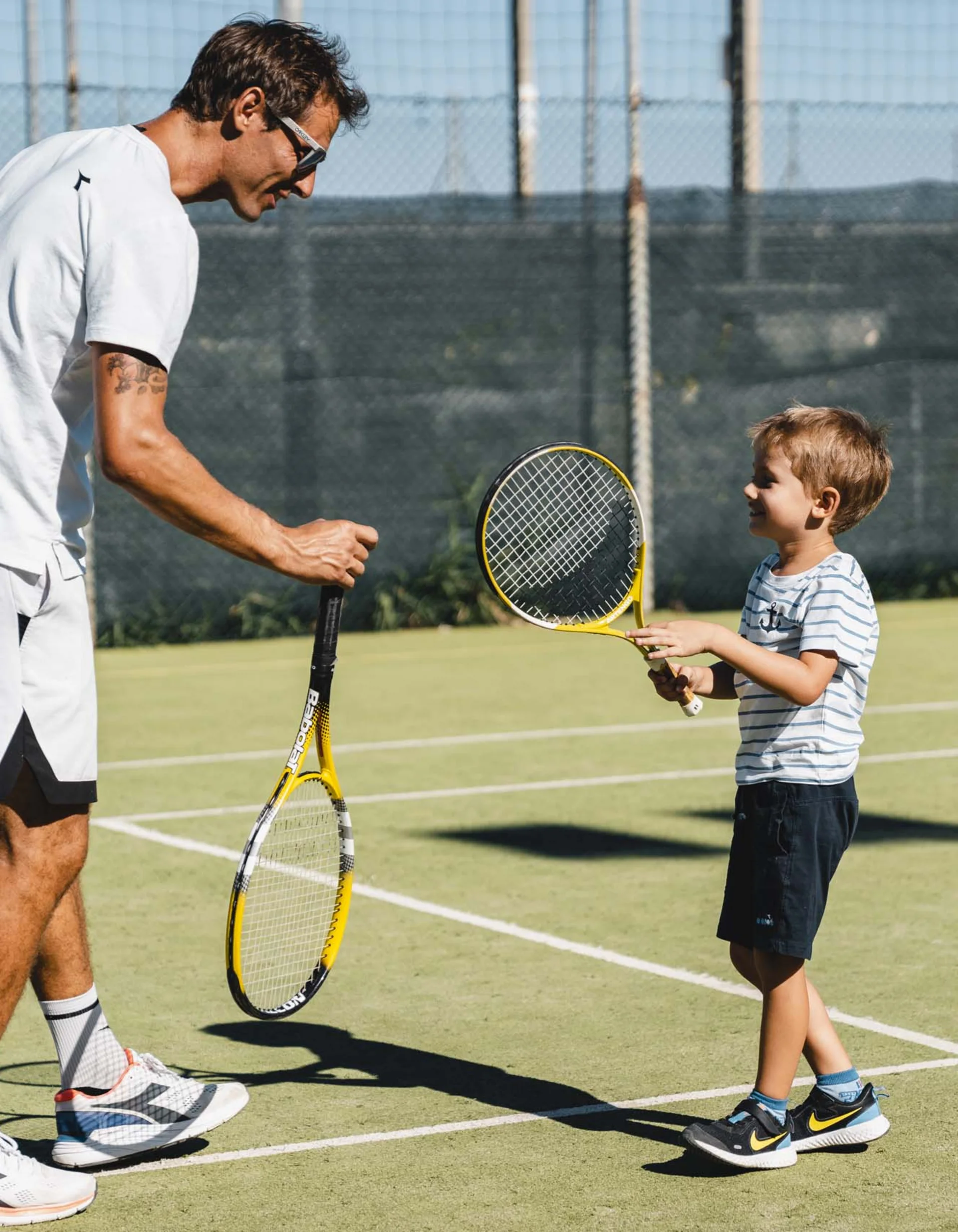 Mann und Kind spielen Tennis auf einem Outdoor-Platz