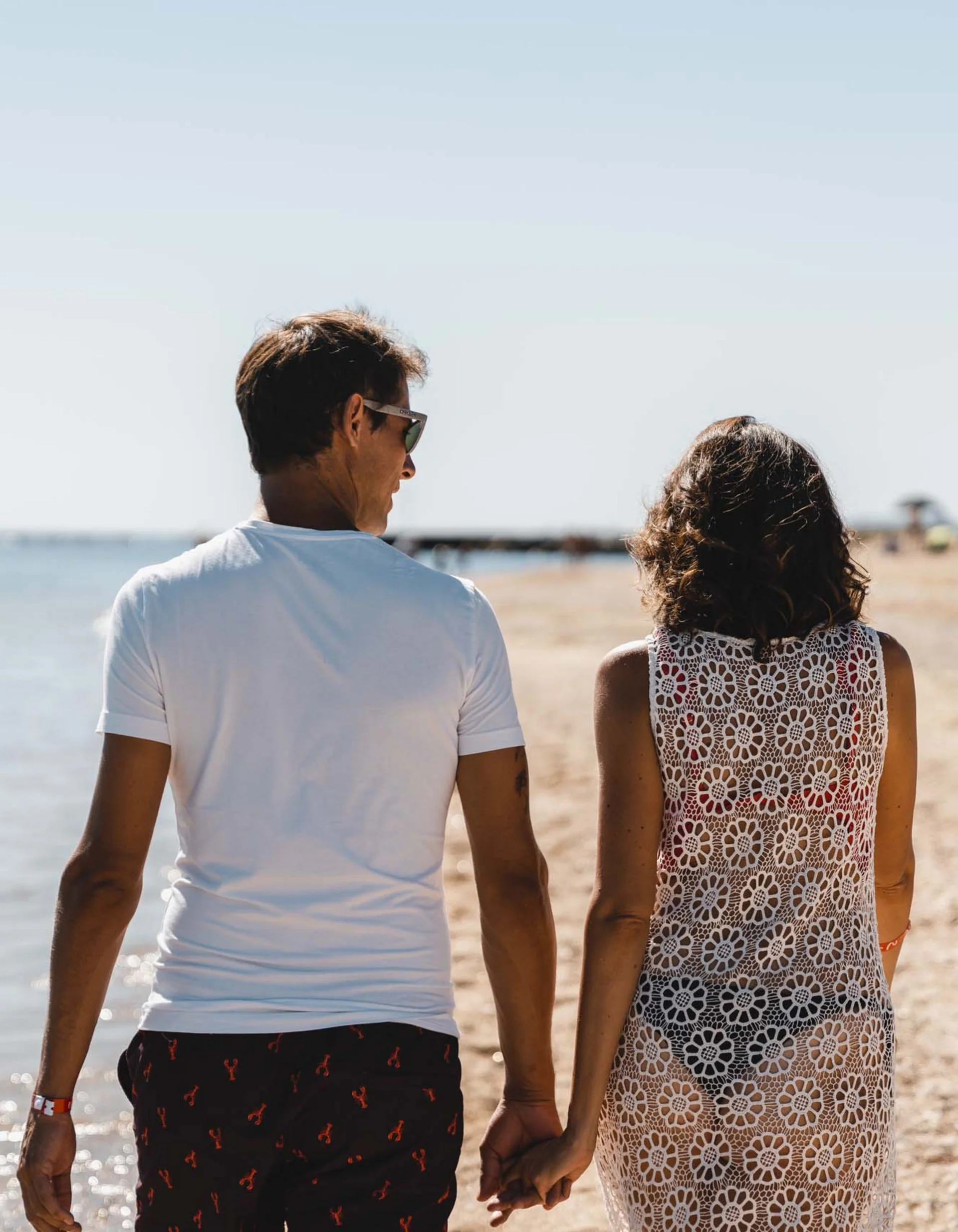 Paar hält Händchen und spaziert am Strand entlang