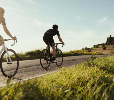 Due ciclisti in abbigliamento nero pedalano su strada in campagna al tramonto