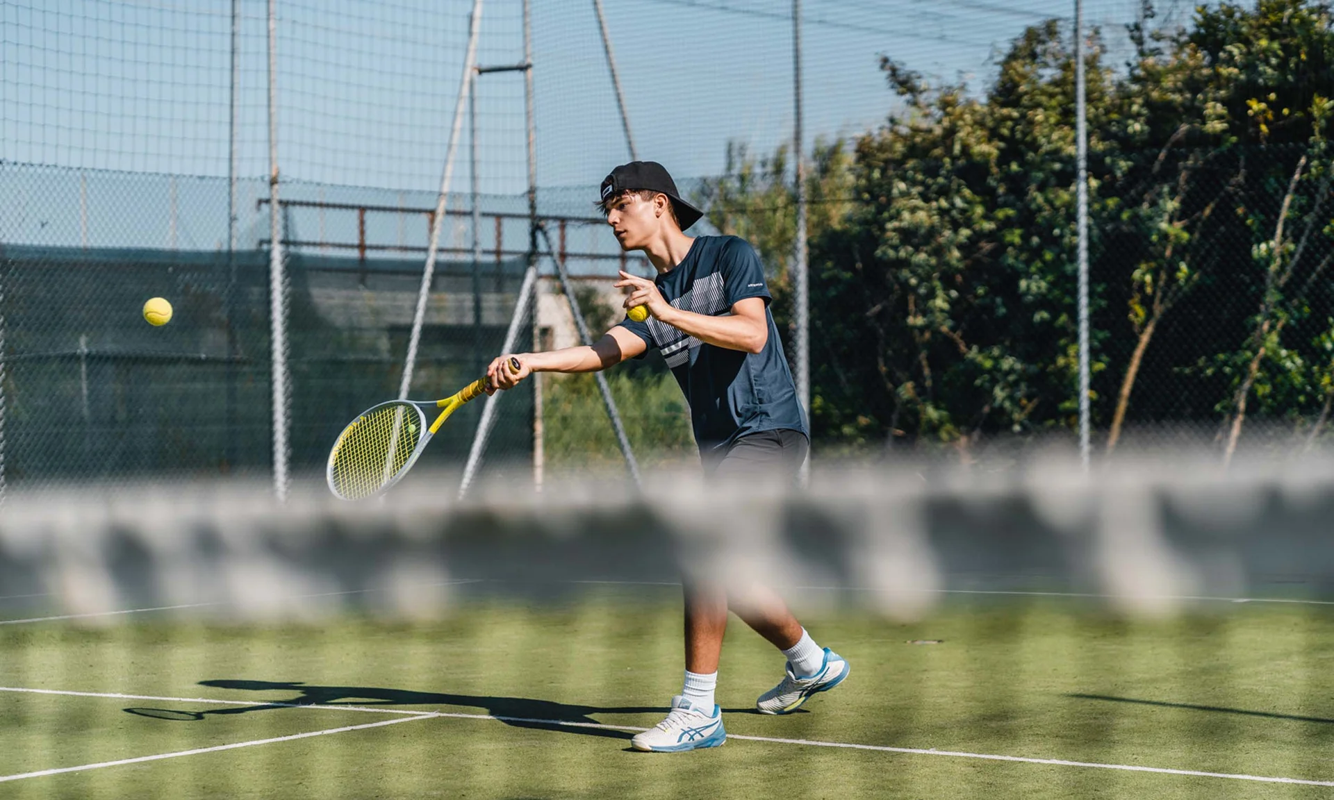 Tennisspieler schlägt einen Ball auf einem Außenplatz