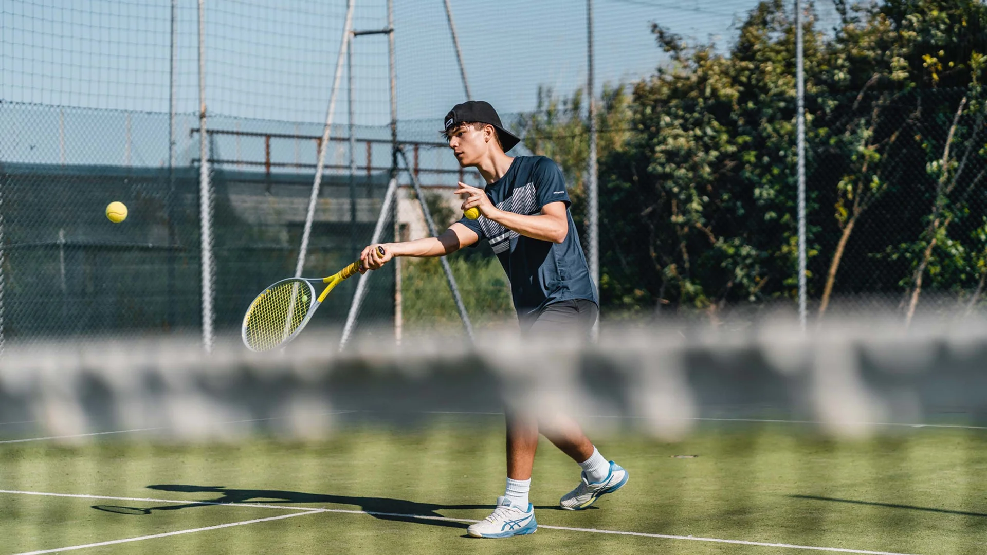 Tennisspieler schlägt einen Ball auf einem Außenplatz
