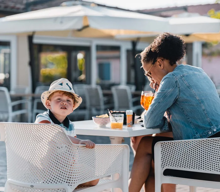 Bambino con cappello e donna seduti a un tavolo all'aperto con bevande